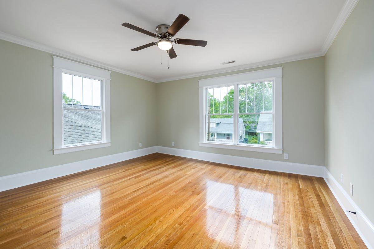 Empty room with hardwood floors, sage walls, and a five-blade ceiling fan